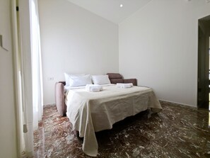 A bedroom with a bed, pillows, a bedside table, and a marble floor. - Domus Arconti (Reggio Calabria)