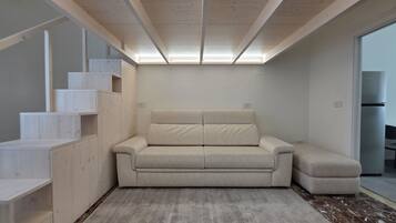 A modern interior with a sofa, built-in shelving, and a large window.