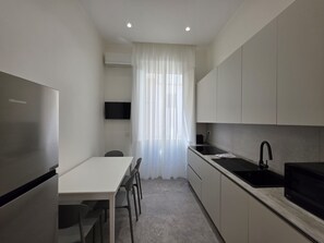 A compact kitchen with a refrigerator, a microwave, a sink, and a dining area with chairs.