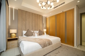 A modern bedroom with a large bed, bedside lamps, a wooden wardrobe, and a ceiling light fixture. - Gogoto11 2BR Premium Infinity Pool & Burj View (Dubai)