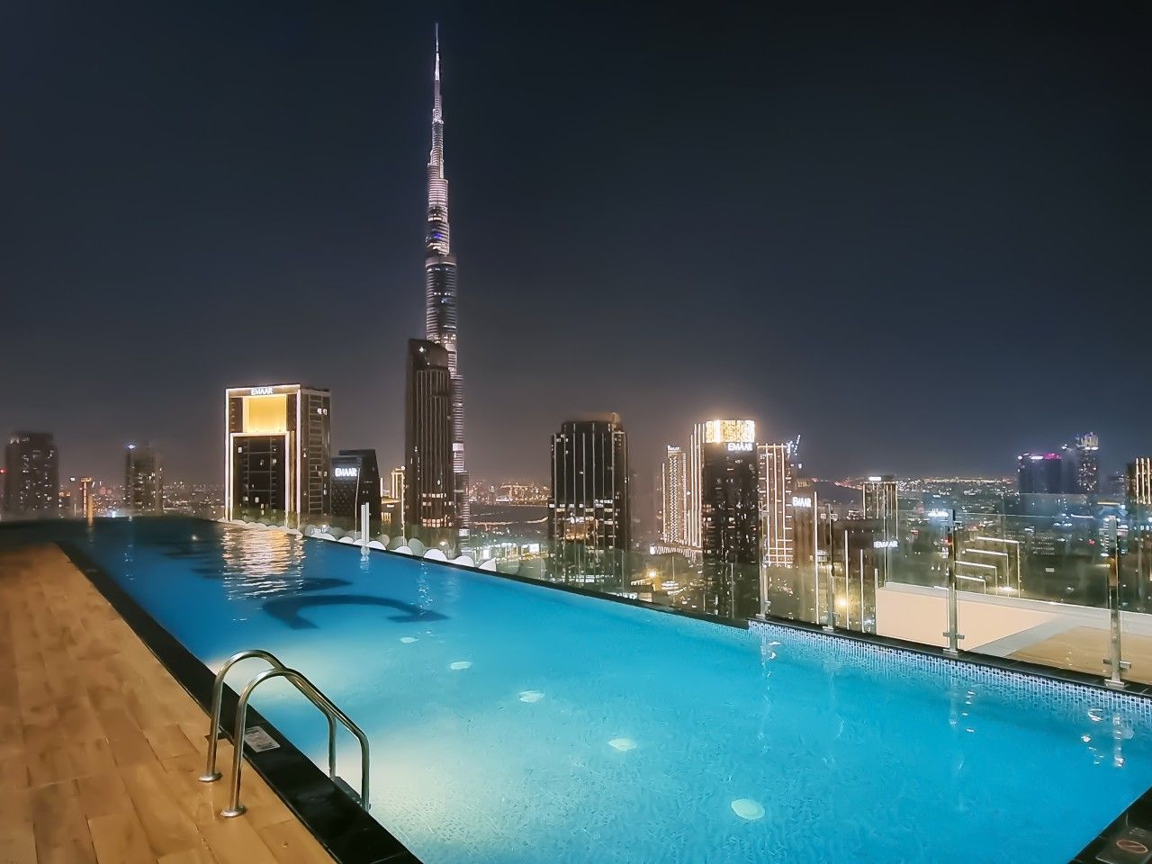 Une piscine sur le toit offrant une vue sur les toits de la ville la nuit.