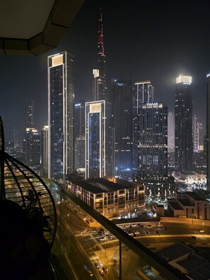 A nighttime cityscape with illuminated skyscrapers and a view of a parking area. - Gogoto11 2BR Premium Infinity Pool & Burj View (Dubai)