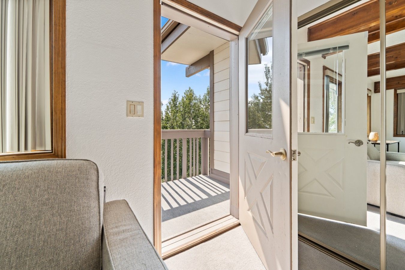 Una habitación con puerta que da a un balcón, un sofá y una ventana con persianas.