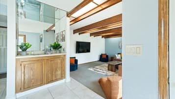 Un interior moderno con área de cocina, sala de estar con asientos y televisor visible.