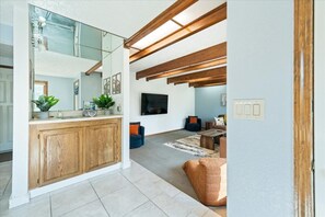 A modern interior with a kitchen area, a living room with seating, and a visible television.
