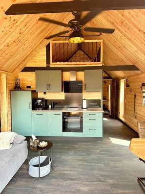 Una cocina compacta con ventilador de techo, un comedor con mesa y sillas, y una zona de estar acogedora con un sofá.