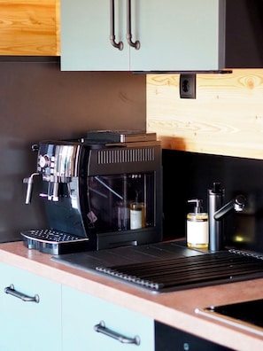 Una cafetera sobre una encimera con un panel de madera y un mueble arriba.