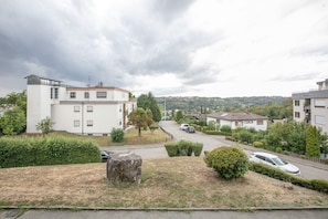 A residential area with modern buildings, a road, and a large rock in the foreground.