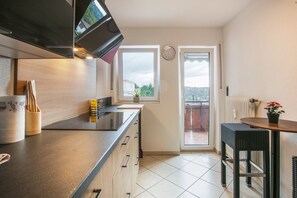 A modern kitchen with a built-in oven, a window with a view, and a dining area with a table and chairs.