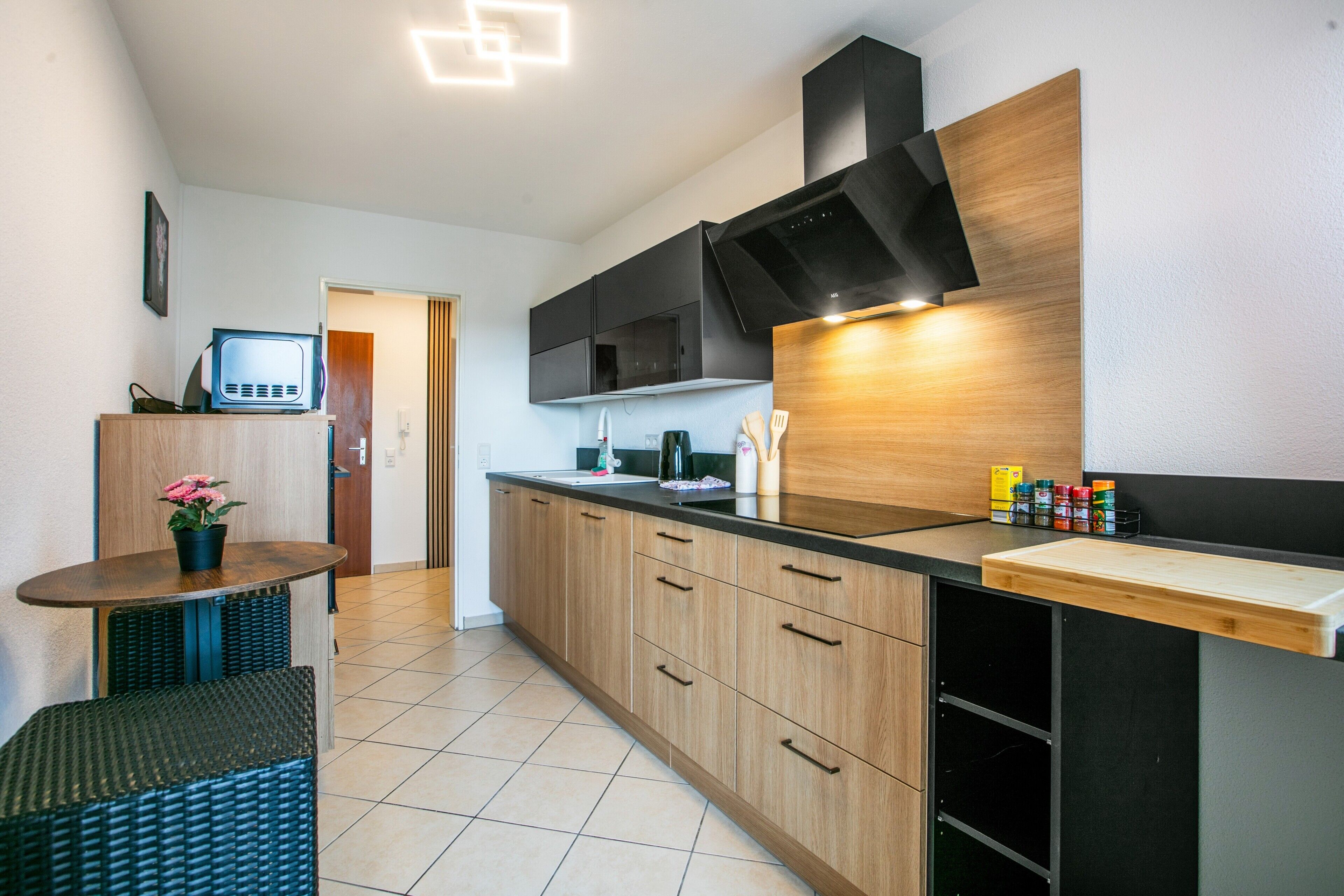 A modern kitchen with wooden cabinets, a black countertop, and a built-in microwave.
