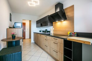 A modern kitchen with wooden cabinets, a black countertop, and a built-in microwave.