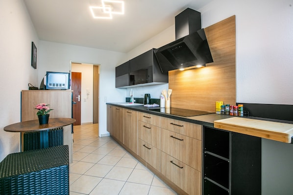 A modern kitchen with wooden cabinets, a black countertop, and a built-in microwave.