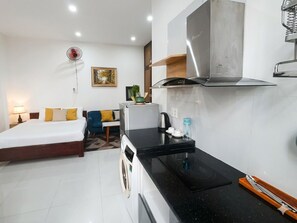 Une chambre d’hôtel compacte comprenant un lit, une petite kitchenette, un lave-linge et un coin repas.