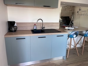 A modern kitchen with a built-in sink, a coffee maker, and a bottle of dish soap. - Beachfront house renovated in 2025, located on a quiet cul-de-sac 20 meters from the GR34. (Plouescat)