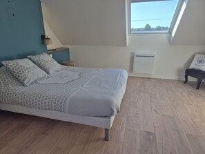 A bedroom with a bed, a window, a bedside table, and a chair. - Beachfront house renovated in 2025, located on a quiet cul-de-sac 20 meters from the GR34. (Plouescat)