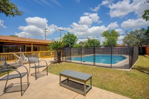 A backyard with a swimming pool, a covered patio with chairs, and a wooden deck. - The Airman House: Pool/Hot Tub Fun By Lackland AFB (San Antonio)