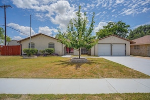 A residential property with a two-story brick house, a garage, and a well-maintained lawn. - The Airman House: Pool/Hot Tub Fun By Lackland AFB (San Antonio)