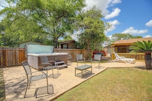 An outdoor patio with a hot tub, seating, and a wooden fence. - The Airman House: Pool/Hot Tub Fun By Lackland AFB (San Antonio)