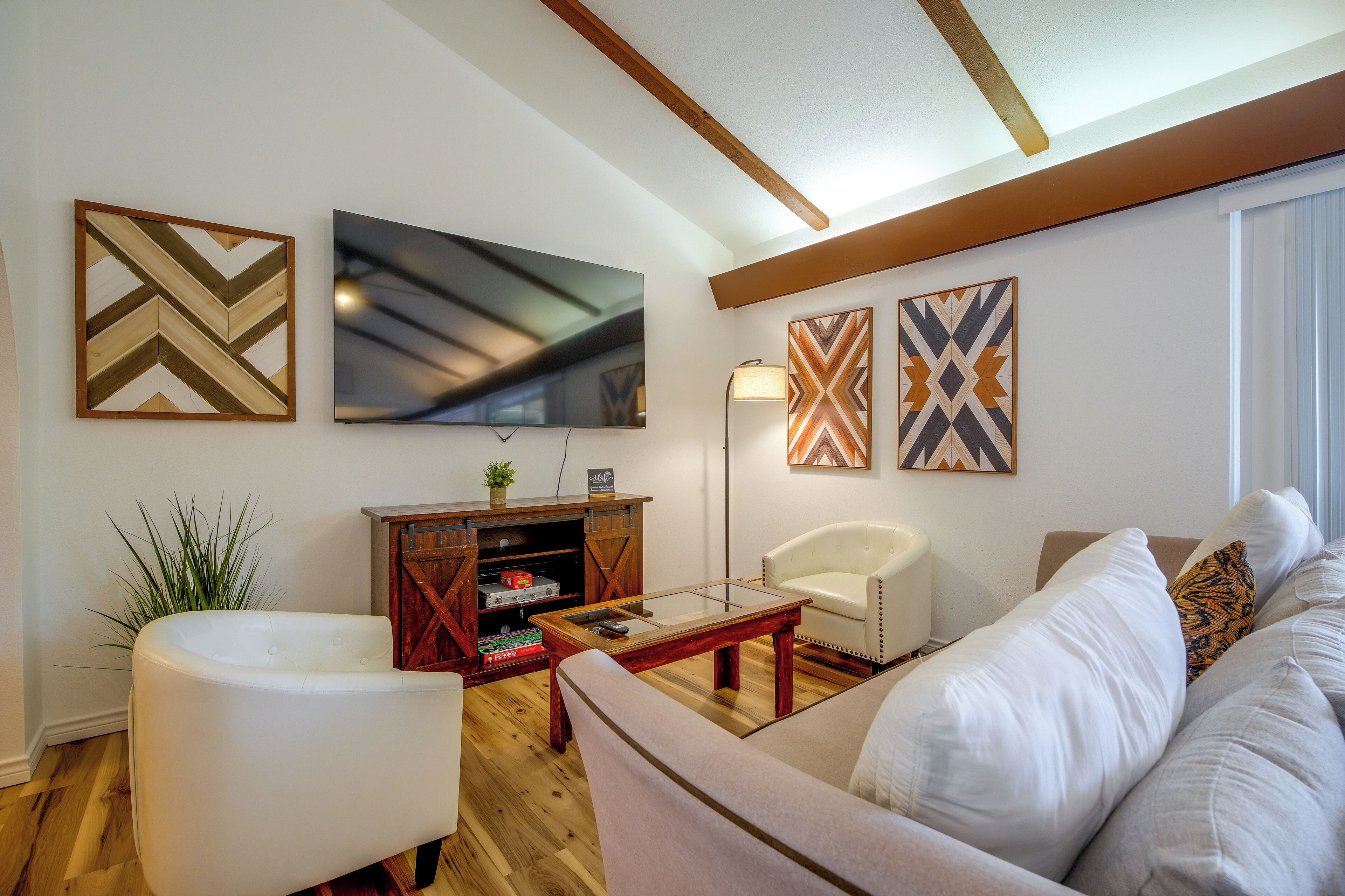 A living room with a sofa, a coffee table, a TV, and decorative wall art.