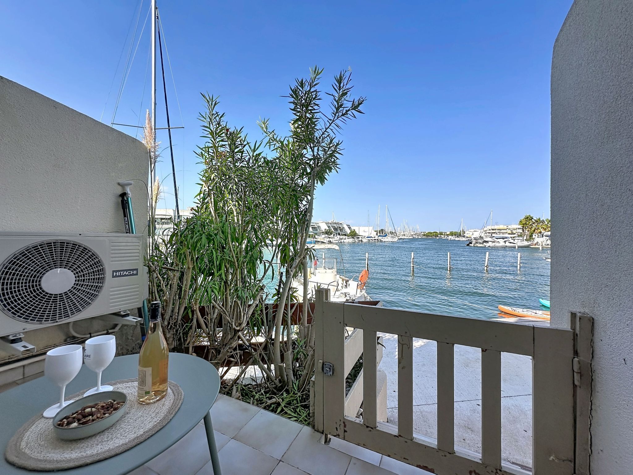 A balcony with a table, a fan, and a view of a marina with boats.