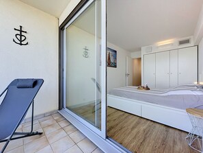 A bedroom with a bed, a sliding glass door, a chair, and a painting. - Ulysse Port de Plage by Interhome (Port Camargue)