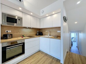 A modern kitchen with white cabinets, a microwave, a toaster, and a sink. - Ulysse Port de Plage by Interhome (Port Camargue)