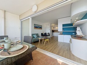 A modern living space with a dining area, kitchen, and a large mirror reflecting the room. - Ulysse Port de Plage by Interhome (Port Camargue)