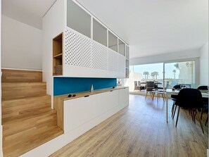 A modern kitchen with a wooden staircase, a blue countertop, and a dining area with a view. - Ulysse Port de Plage by Interhome (Port Camargue)
