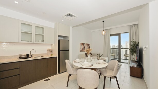 Uma cozinha moderna com frigorífico embutido, sala de jantar com mesa redonda e cadeiras, e varanda com vista para a cidade.