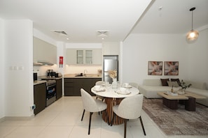 A modern kitchen with a dining area, a sofa, and a coffee table. - Bloomfields 1BR in Creekside 18 (Dubai)