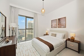 Habitación de hotel con una ventana grande, una cama, dos mesitas de noche con lámparas, un espejo y vistas a la ciudad.