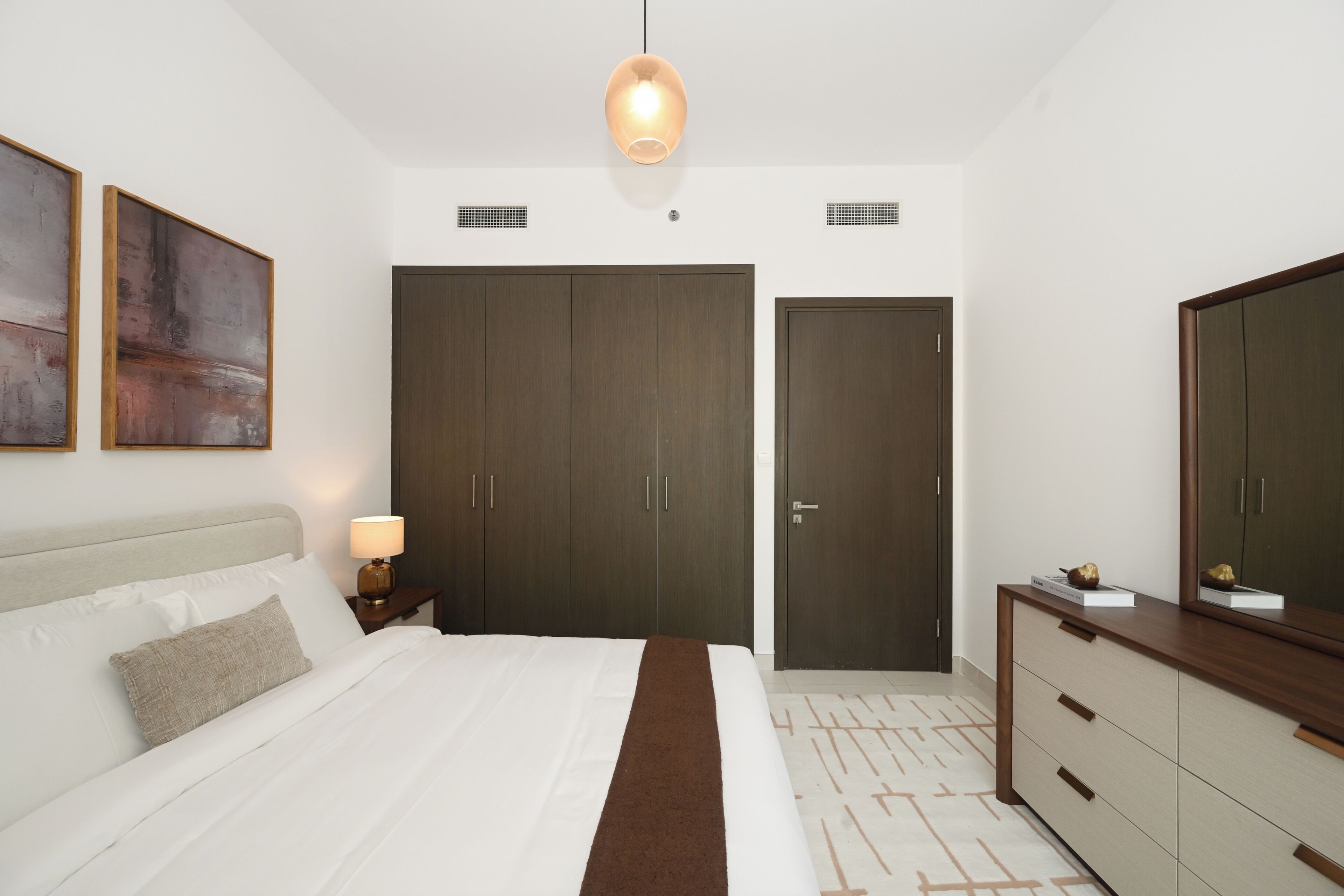Une chambre à coucher comprenant un lit, une table de chevet, une lampe, une armoire et un miroir.