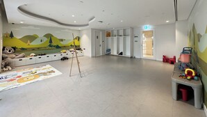 Uma sala de recreação infantil com um mural, armários de armazenamento e uma área de brincadeiras.