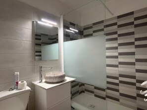 A modern bathroom with a glass shower enclosure, a round sink, and a mirror above the vanity. - Le Petit Patio - Downtown (CAMBO LES BAINS)