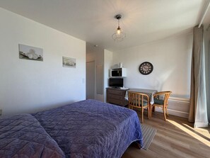 A bedroom with a bed, a desk, a chair, a television, and a clock on the wall. - Le Petit Patio - Downtown (CAMBO LES BAINS)