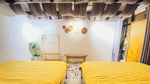 A room with two beds, a small table, a potted plant, and a wall with circular decorations. - 3BR Old Quarter Stay | Walk to Lake & Beer Street | Rooftop & Soaking Tub (Hà Nội)
