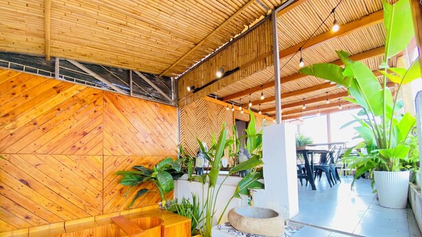 A wooden interior with seating and potted plants. - 3BR Old Quarter Stay | Walk to Lake & Beer Street | Rooftop & Soaking Tub (Hà Nội)