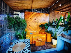 A wooden reception desk with a seating area, potted plants, and a patterned wall. - 3BR Old Quarter Stay | Walk to Lake & Beer Street | Rooftop & Soaking Tub (Hà Nội)