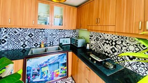 A kitchen with wooden cabinets, a tiled backsplash, and a gas stove. - 3BR Old Quarter Stay | Walk to Lake & Beer Street | Rooftop & Soaking Tub (Hà Nội)