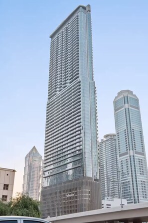 A tall, modern skyscraper with a glass facade and a distinctive, curved design at the top. - Stylish 2BR in Paramount Infinity Pool   (Dubai)