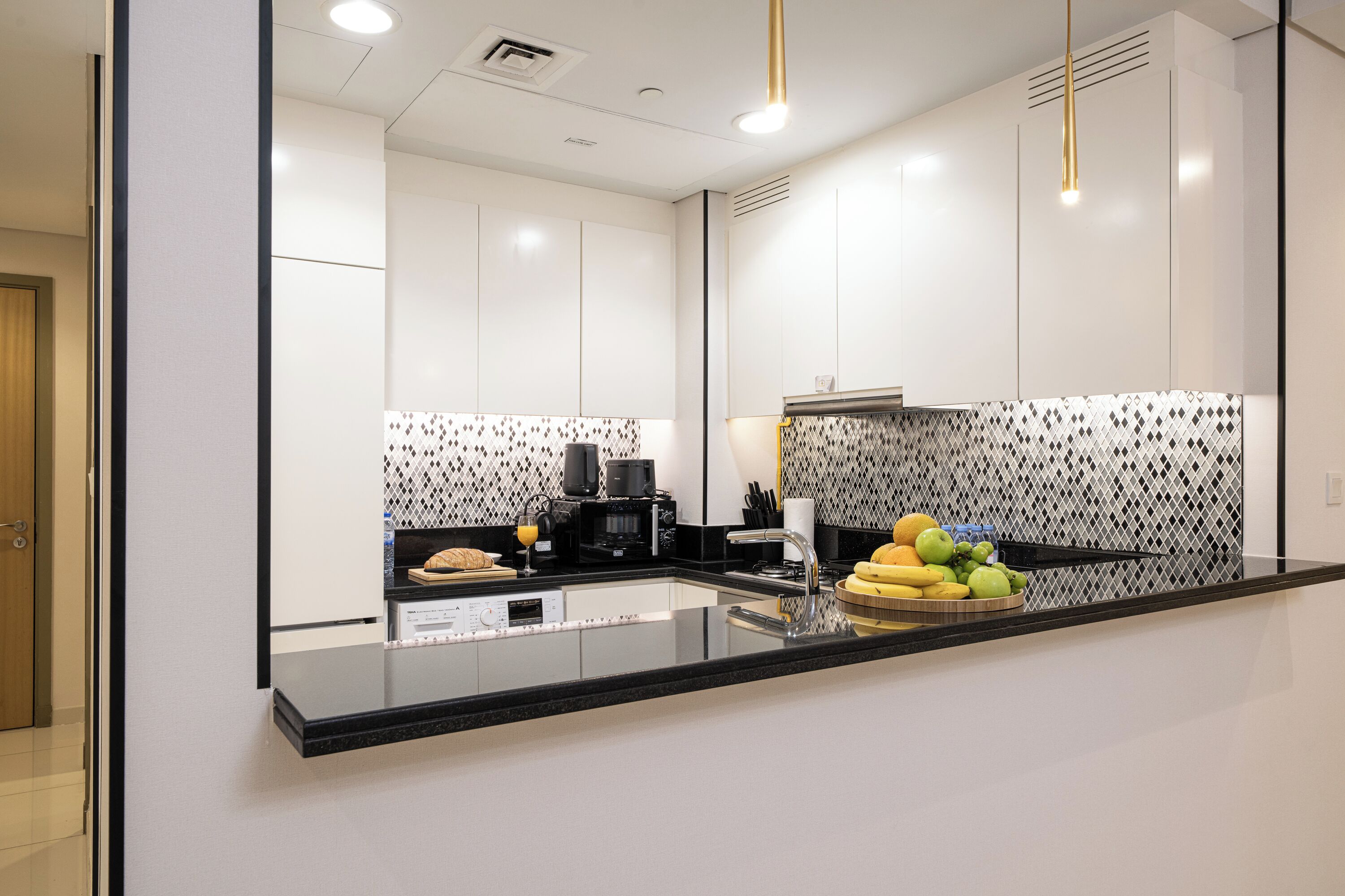 A modern kitchen with a black countertop, stainless steel appliances, and a patterned backsplash.
