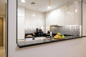A modern kitchen with a black countertop, stainless steel appliances, and a patterned backsplash. - Stylish 2BR in Paramount Infinity Pool   (Dubai)