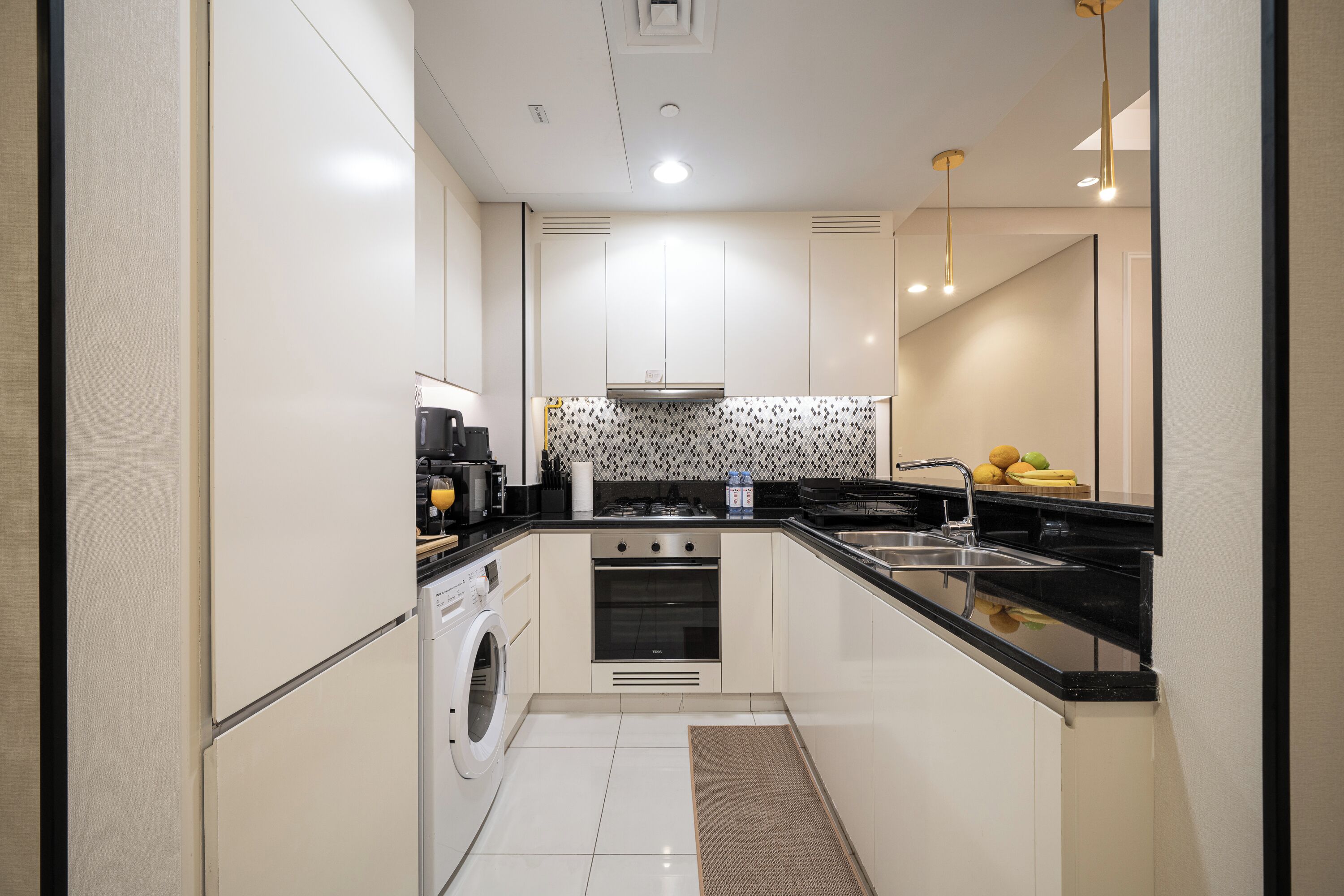 A compact kitchen with a washing machine, oven, and a sink.