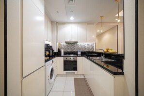 A compact kitchen with a washing machine, oven, and a sink. - Stylish 2BR in Paramount Infinity Pool   (Dubai)