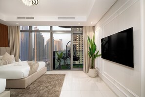 A modern bedroom with a large bed, a TV, and a balcony with a view of high-rise buildings. - Stylish 2BR in Paramount Infinity Pool   (Dubai)