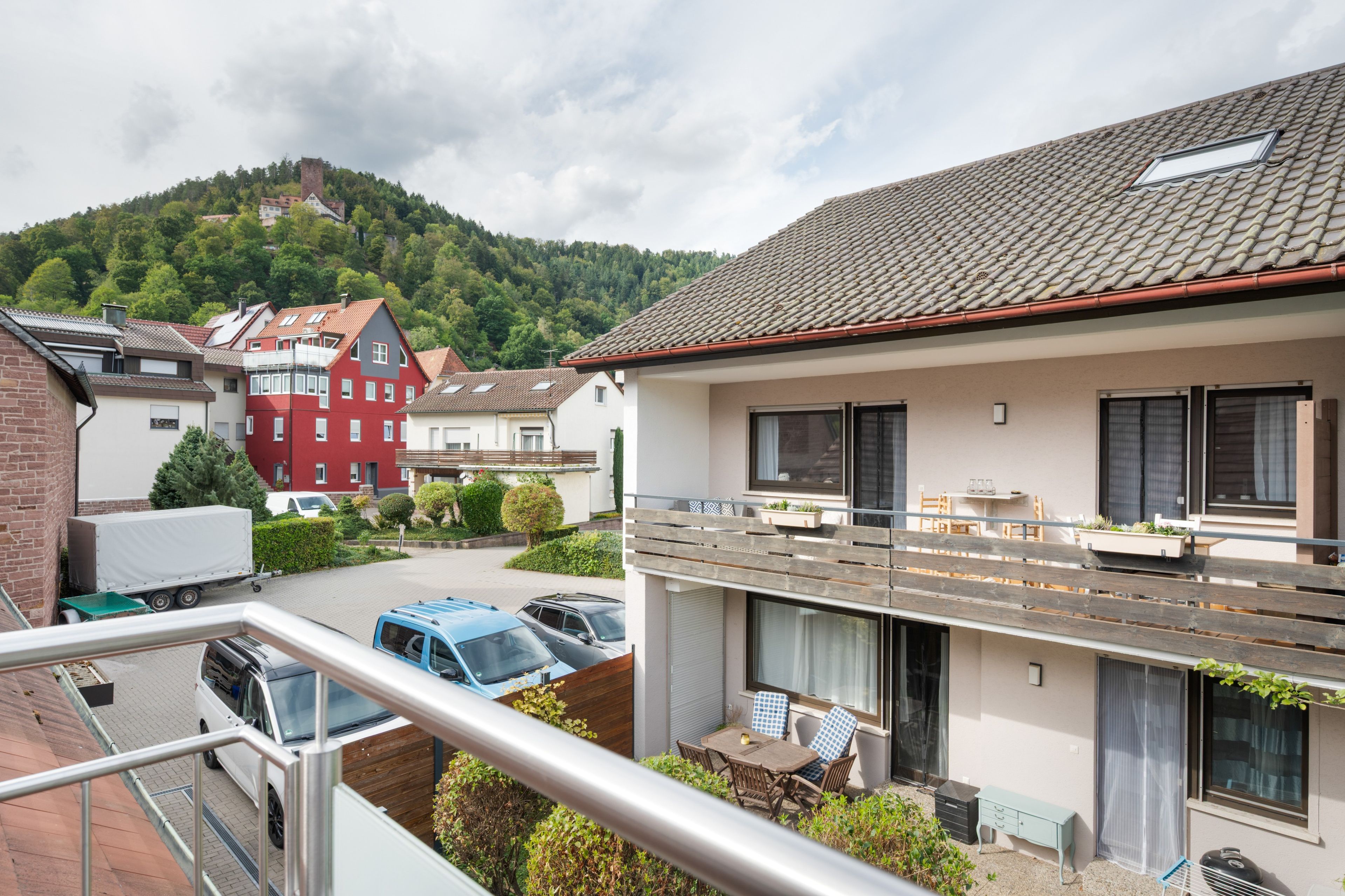 Un immeuble résidentiel doté d’un balcon, d’un espace de stationnement et offrant une vue sur une colline.