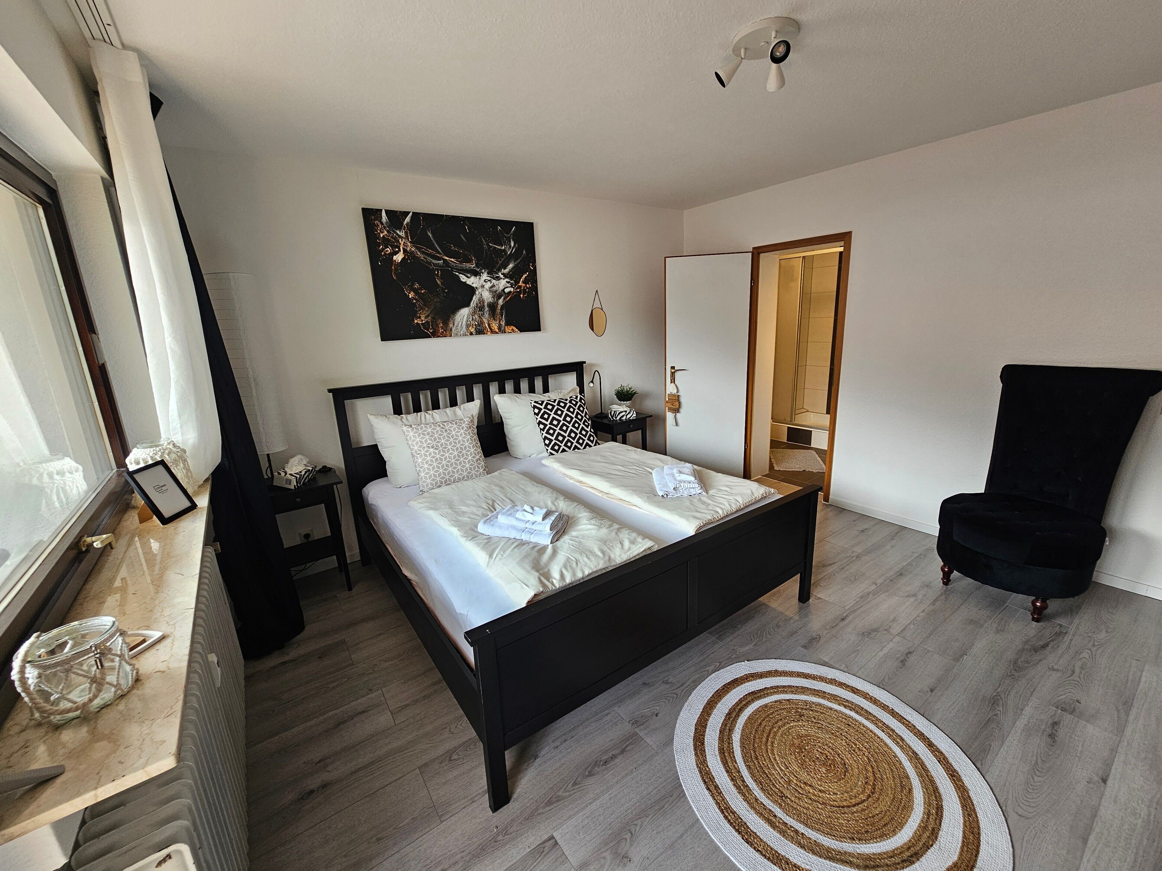 Un dormitorio moderno con cama, mesitas de noche, una silla y un cuadro.