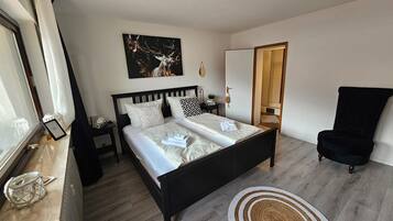 Un dormitorio moderno con cama, mesitas de noche, una silla y un cuadro.