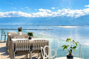 An outdoor dining area with tables and chairs, overlooking a body of water and mountains. - MR.6 sea view Inn (Dali City)
