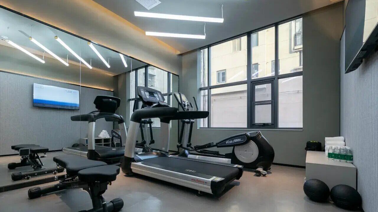 Ein Fitnessstudio mit Laufbändern, Crosstrainern und Kurzhanteln.